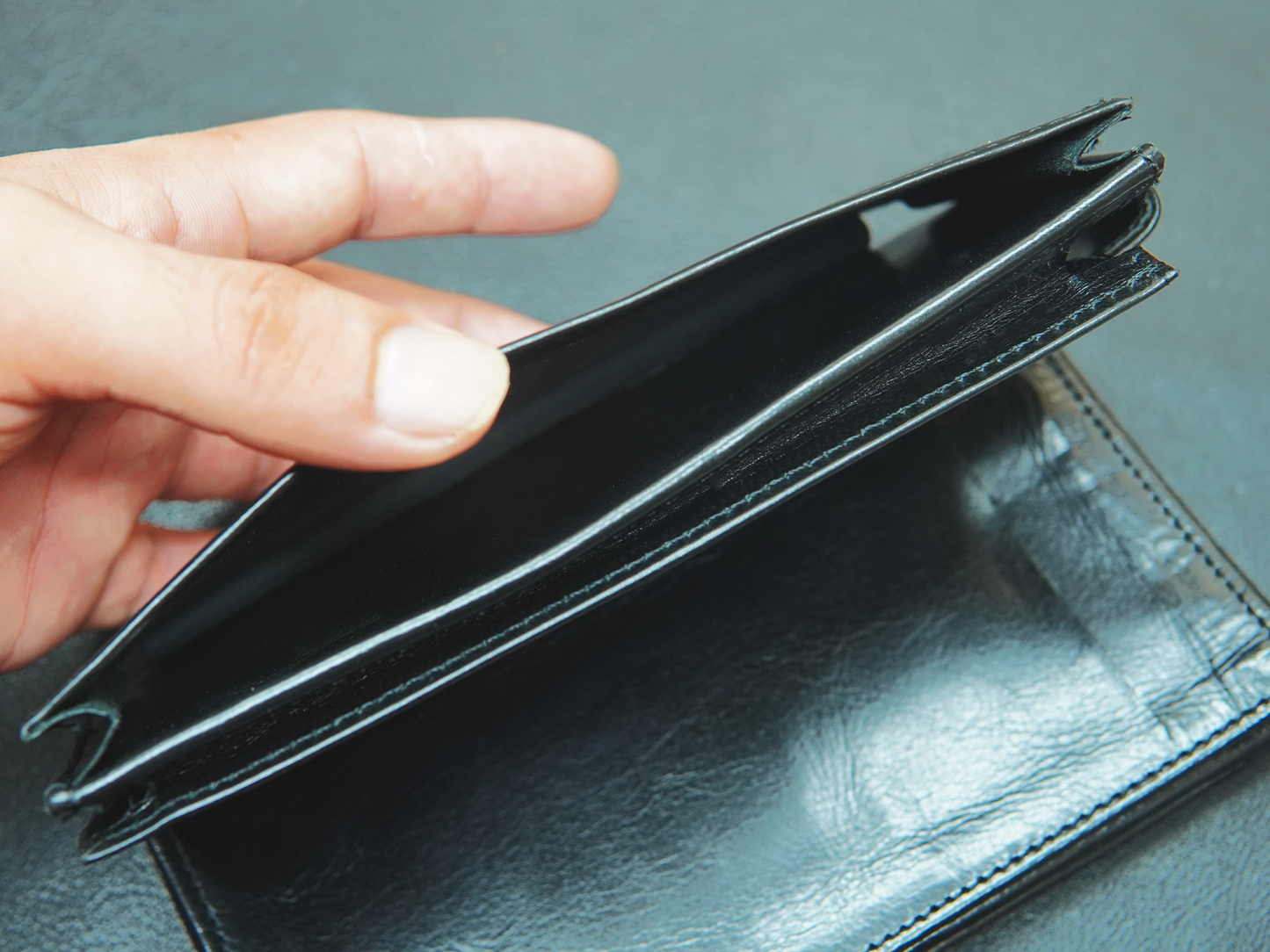Hand holding an empty black leather wallet