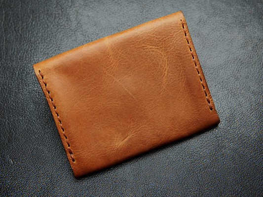 Back of hand-stitched leather wallet showing precise artisan finishing and compact minimalist profile.