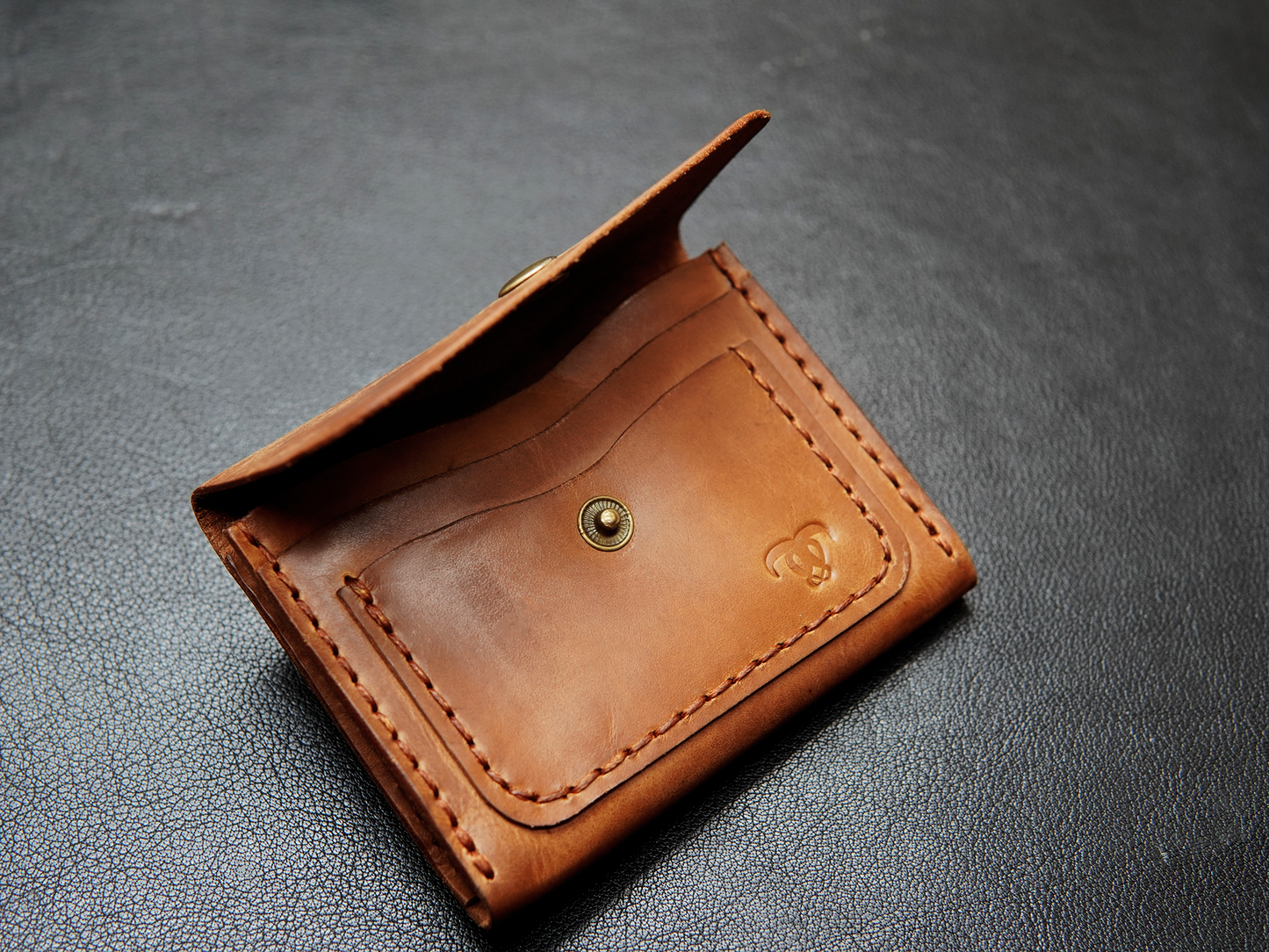 Handmade full-grain leather card holder on desk – compact design made for simple carry.