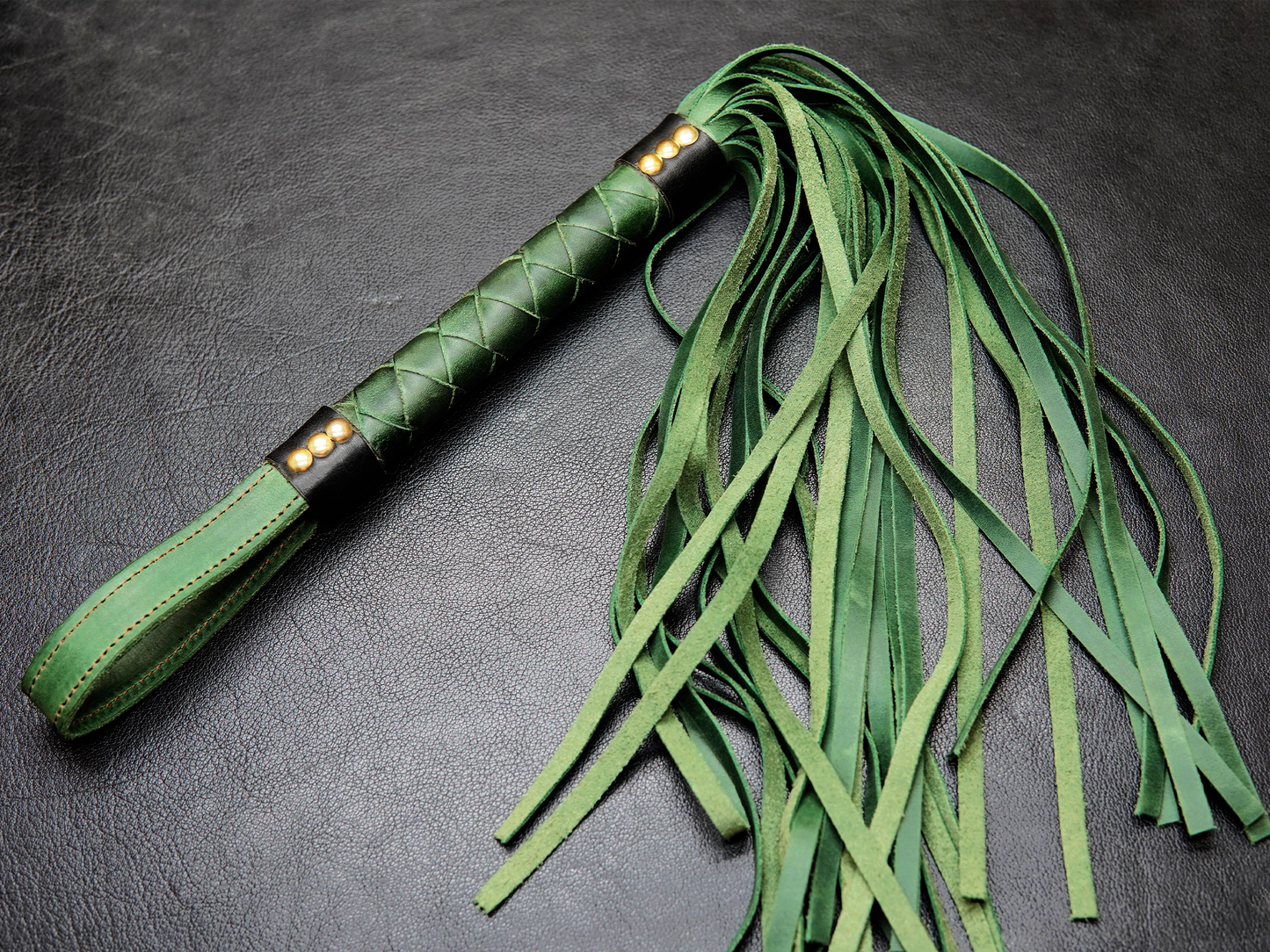 Full view of green Fits Flogger by Bovidas – leather flogger with braided handle and soft falls"