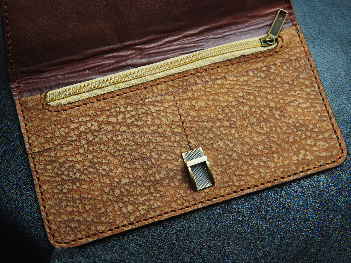 Handcrafted brown leather clutch close-up showing rich texture and artisan stitching