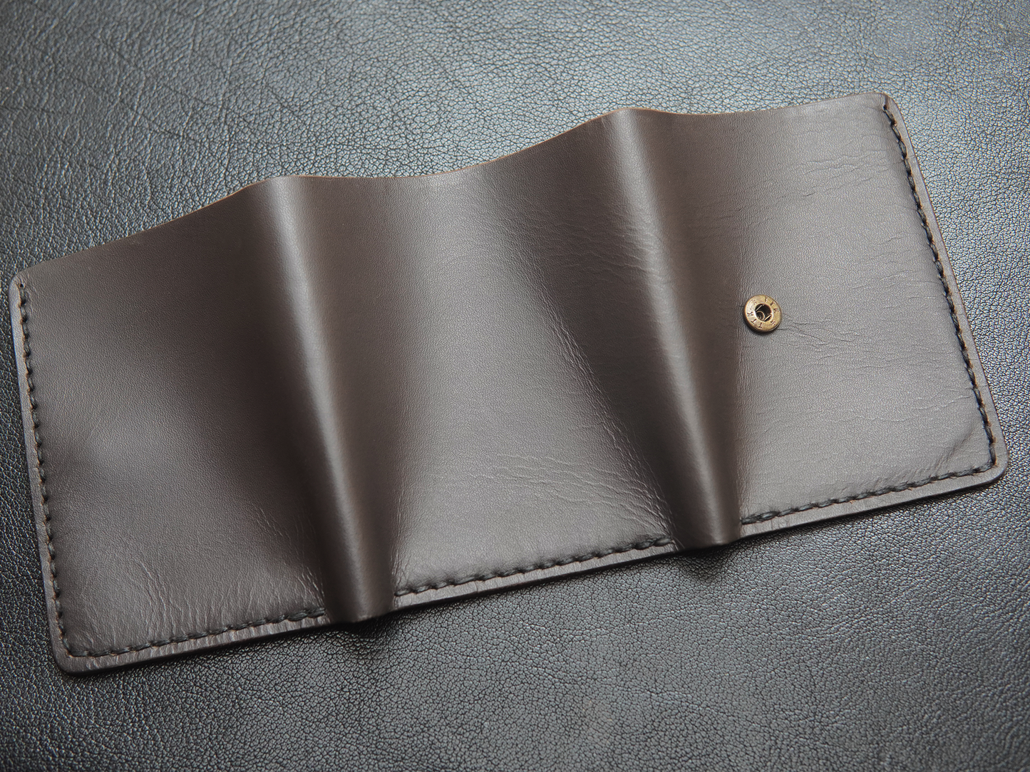 Back of handcrafted leather wallet showing stitching detail and slim trifold shape for men