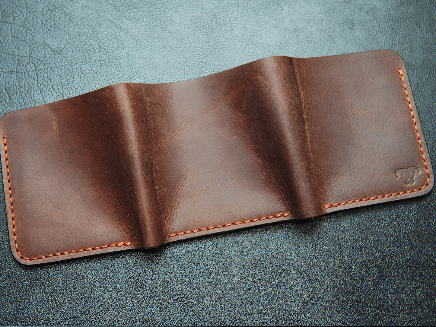 Back of large capacity handmade leather wallet with visible stitching and classic trifold shape.