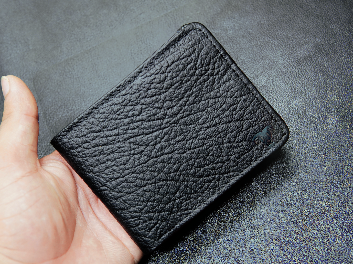 Slim black leather wallet held in hand, ideal minimalist wallet for men’s pocket
