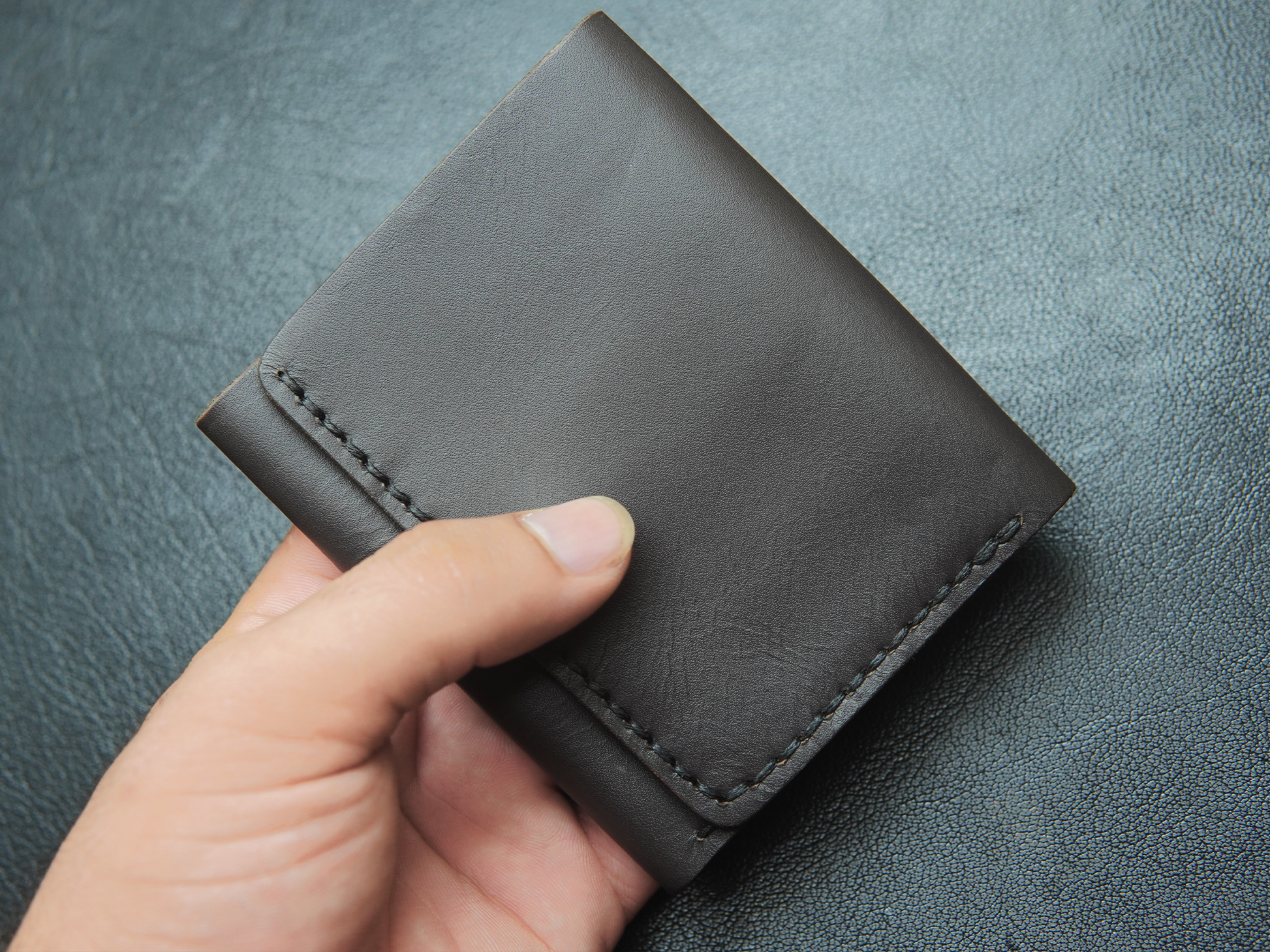 Trinity wallet held in hand – full-grain leather trifold wallet with spacious yet slim profile.
