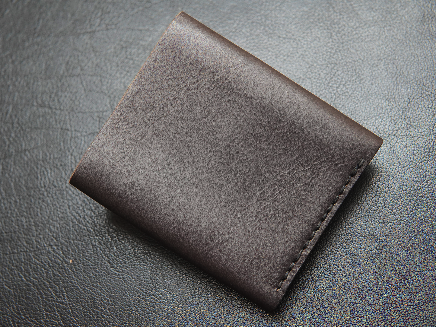 Back of handcrafted leather wallet showing stitching detail and slim trifold shape for men.