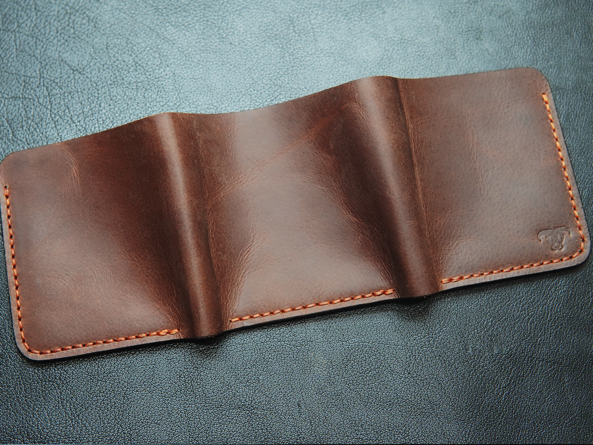 Back of large capacity handmade leather wallet with visible stitching and classic trifold shape.